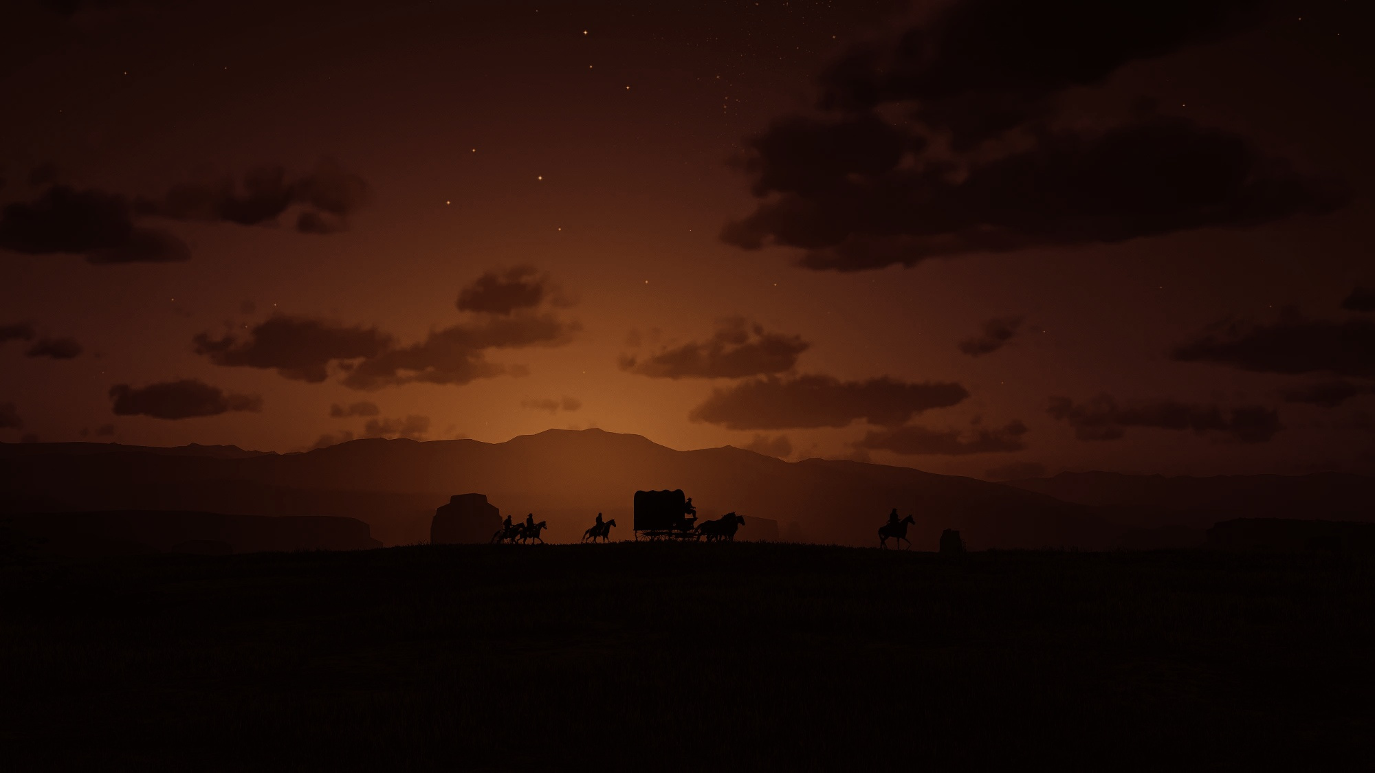 A wagon train and outriders silhouetted on the horizon at dusk